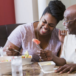 adult daughter helping elderly father to eat