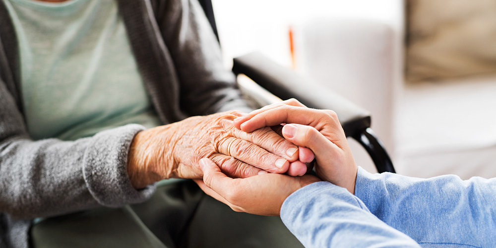 man holding elderly woman's hands